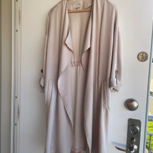 Rosa Trenchcoat - Trenchcoat i ”smutsrosa” färg, gott skick, men faller mig inte riktigt i smaken därav säljer jag! 