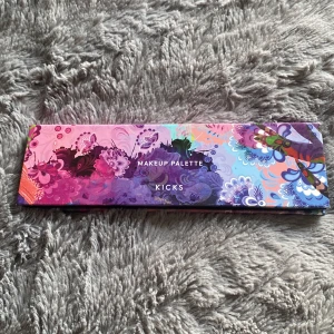 Makeup Palette från KICKS - Säljer en superfin makeup palette från KICKS med fyra högpigmenterade nyanser: Beach Sand, Sunset, Heat Wave och Sunkissed. Perfekt för både ögonskugga och rouge! Paletten har en mix av matta och skimrande finishar, vilket gör den perfekt för att skapa olika looks. Förpackningen är färgglad och mönstrad, vilket gör den extra rolig att ha i sminkväskan. Inkluderar en spegel för enkel applicering on-the-go!