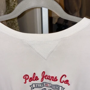 Polo Ralph lauren Långärmad vit tröja - Säljer en stilren vit tröja från Polo Ralph lauren. av Ralph Lauren. Tröjan har en klassisk design med broderad logotyp i rött och blått framtill. Tillverkad i bomull för en bekväm passform. Perfekt för en avslappnad look.