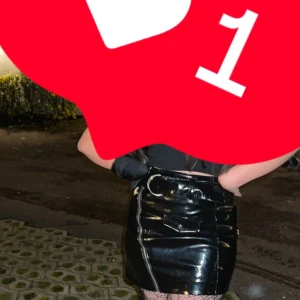 Svart skin  kjol  - Snygg svart glansig kjol med hög midja och bälte. Perfekt för en kväll ute. Kjolen har en tight passform och ger en stilren look.