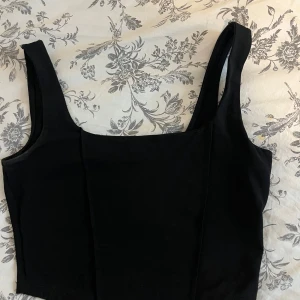 Svart kort top från Gina i storlek S. Knappt använd 🖤 - Snygg svart linnetopp från Gina Tricot med breda axelband. Perfekt för en stilren look och enkel att matcha med olika outfits.