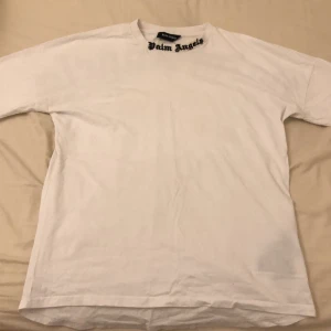 Vit t-shirt från Palm Angels - Snygg vit t-shirt från Palm Angels med stort tryck i svart på baksidan. Den har en normal passform och är kortärmad, perfekt för en avslappnad stil.