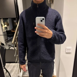 Mörkblå fleecejacka från John Henric - Säljer en stilren mörkblå fleecejacka från John Henric. Jackan har en hög krage och dragkedja framtill samt praktiska fickor med dragkedja. Perfekt för kyliga dagar. 