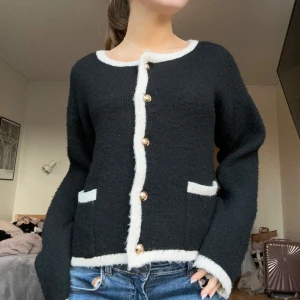 Svart kofta med vita detaljer - Snygg svart kofta med vita kanter och guldknappar. Den har långa ärmar och två fickor fram. Perfekt för en stilren look.💓 Nypris: 600kr