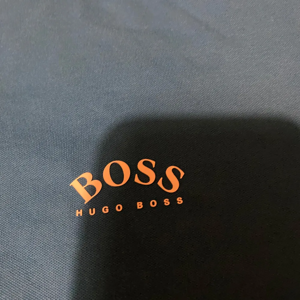 Snygg blå pikétröja från Boss med klassisk krage och knappar. Tröjan har vita och mörkblå ränder på kragen och ärmsluten. Då den inte kommer till användning längre.. T-paidat.