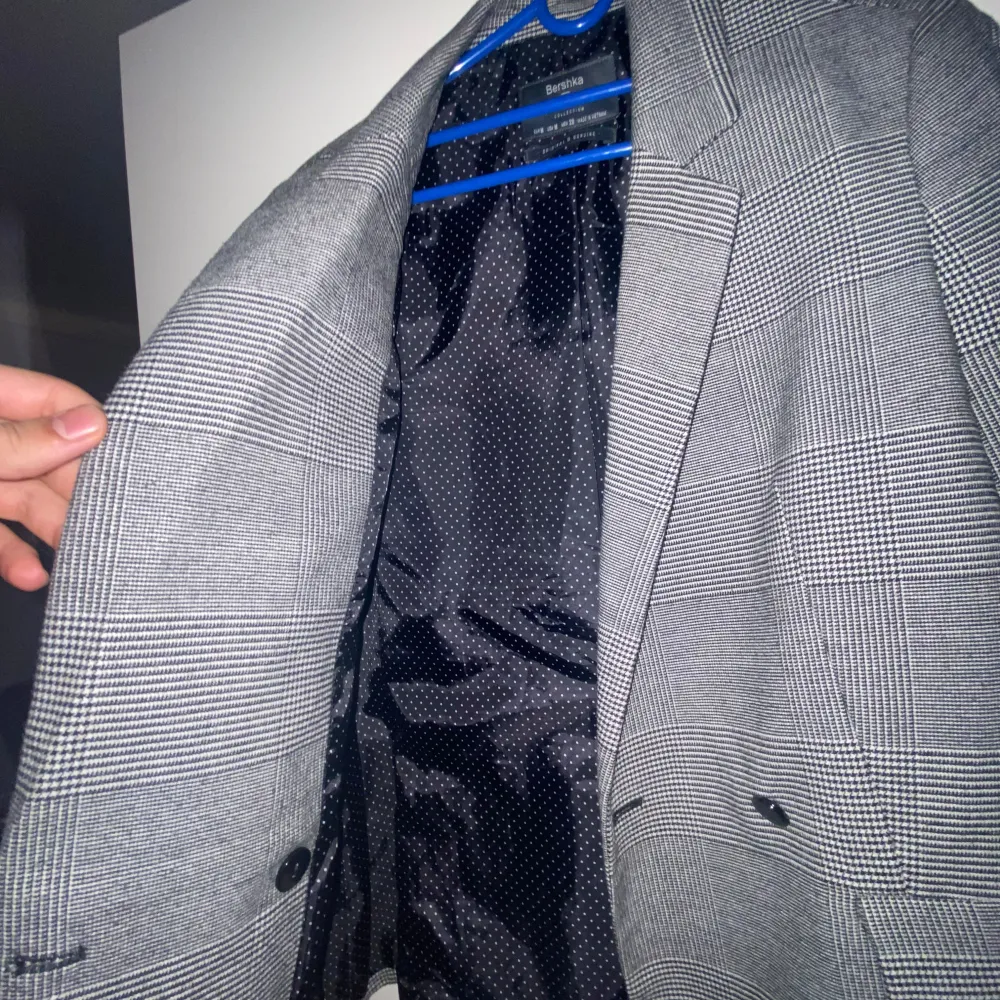 Snygg grå rutig kavaj med klassisk passform. Kavajen har två knappar framtill och fickdetaljer. Perfekt för en stilren look. Priset är inte hugget i sten. Puvut & Bleiserit.