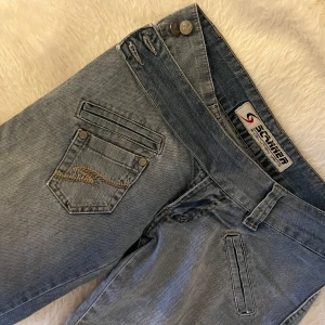 Lågmidjade utsvängda jeans - Trendiga lågmidjade jeans med coola detaljer och fickor! Köpta i Brasilien men skulle säga att de passar S/M. Jag brukar passa i jeans med storlek S som är lite ”större” i storleken och M som är ”mindre” i storleken och det är storleken på dessa jeans. Passar även bra i längden för mig som är 169cm. Pris kan diskuteras vid snabb affär! Finns fler lågmidjade jeans, trendiga tröjor och väskor billigt i min profil!