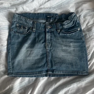 Lågmidjad y2k Stockholmsstil jeanskjol med snygga fickor - Snygg blå jeanskjol med klassisk femficksdesign och knappgylf. Perfekt för en avslappnad stil. Kjolen har en kort längd och är tillverkad i slitstarkt denim.