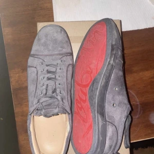 Grå mockasneakers från Christian Louboutin - Snygga grå sneakers i mocka från Christian Louboutin med den ikoniska röda sulan. SJÄLVKLART ÄKTA. Skorna är inte tvättade, går lätt att fixa upp. Skick 7/10, små skador som inte syns vid användning. Hör av er vid frågor! (Köpta på vestiare för 5000kr) kvitto finns. Får med allt vid köp, box, dustbag, skor, kvitto.