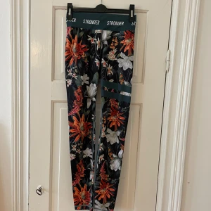 Blommiga leggings från Stronger - Snygga leggings från Stronger med ett färgglatt blommönster i orange, rött och vitt. Tightsen är i fint skick och är sparsamt använda🥰