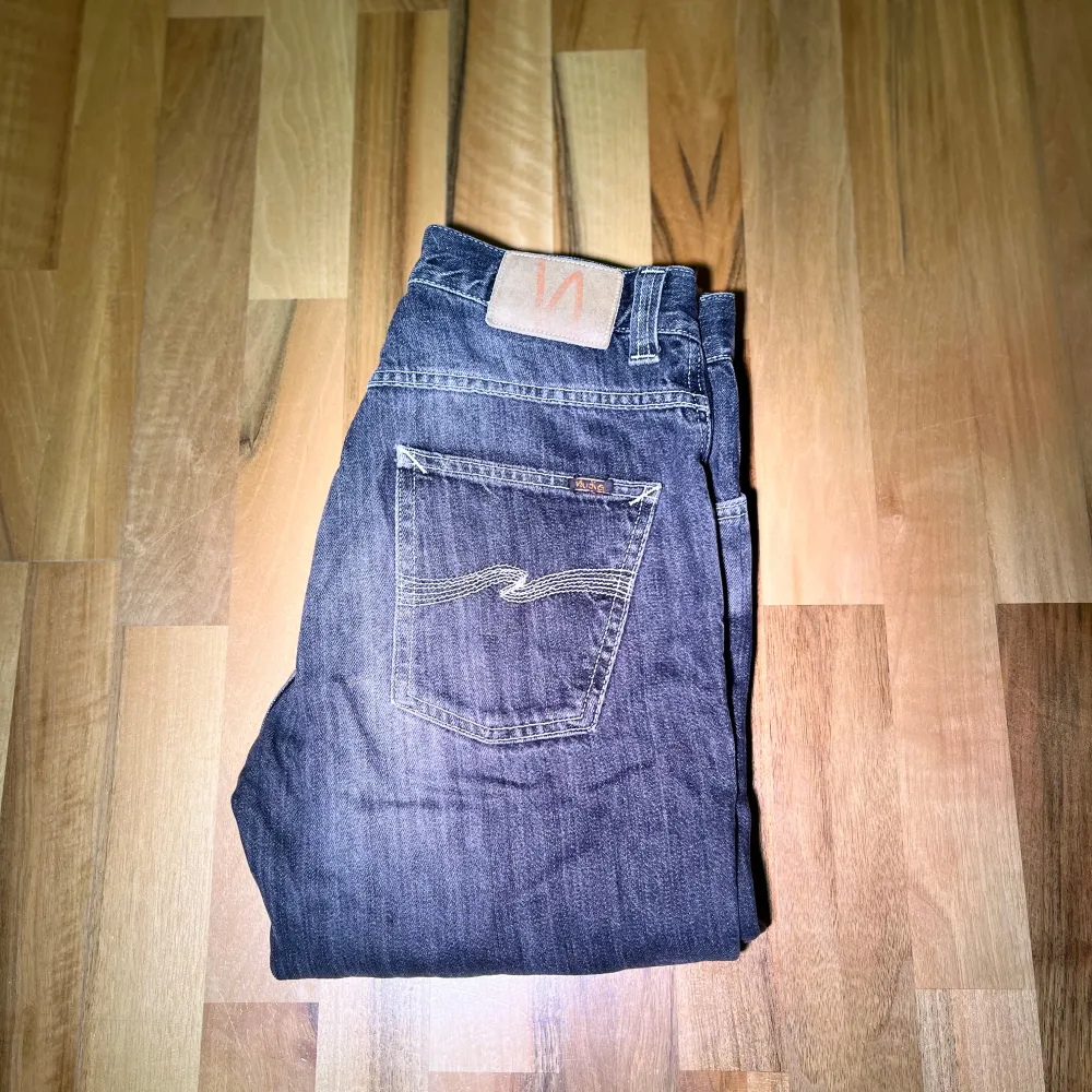 Snygga gråa jeans från Nudie med klassisk femficksdesign och kontrastsömmar. De har en slim passform och är tillverkade i slitstarkt denim. Perfekta för en avslappnad stil. Fet tvätt. Modell: Slim Jim( gammal model) 31/32, finns slitning vid hälen. Ganska mjuk.. Farkut & Housut.