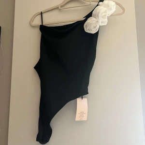 Svart body med vita blommor - Svart body med vita blommor från SHEIN säljer då den var lite stor, den har över en öppen rygg vilket är super fint, prislappen kvar