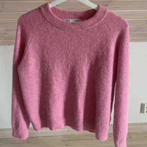 Rosa stickad tröja från Zara - Mysig rosa stickad tröja från Zara med rund halsringning och långa ärmar. Perfekt för kyliga dagar.