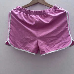 Rosa shorts med vita detaljer - Snygga rosa shorts med vita kanter. Perfekta för en avslappnad stil. Elastisk midja för extra komfort.