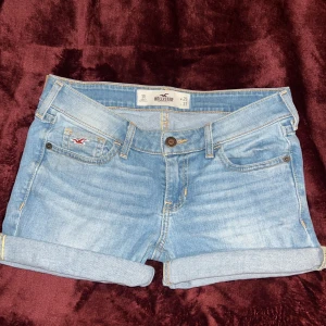 Blå jeansshorts från Hollister - Snygga blå jeansshorts från Hollister med uppvikta ben och klassisk femficksdesign. Perfekta för sommardagar och avslappnade stunder. Märkeslogga på bakfickan och knappstängning framtill. På sista bilden ser ni att det går att vika ned det uppvikta om så önskas 🤗💗