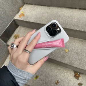 Mobilskal från Amore UF - Mobilskal med en inbyggd hållare för läpprodukter från Amore UF💋Är till IPhone 13/14/15 PRO och rymmer flera olika sorters läppglans samt ger bra skydd för mobilen🤍