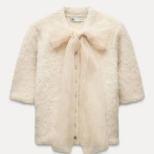 Tröja med rosett - Säljer en superfin vit fluffig kofta från Zara med en rosett framtill. Koftan har trekvartsärmar och knappar längs framsidan. Perfekt nu till våren! Har aldrig använts och är helt ny