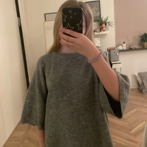 Grå stickad tröja - Mysig grå stickad tröja med trekvartsärmar. Perfekt för kyligare dagar och ger en avslappnad look. Tröjan har en rund halsringning och är lätt att matcha med olika outfits.