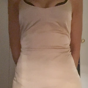 Beige/Champagne Satin klänning - Säljer en stilren beige/champagne satin klänning med smala axelband. Perfekt för en elegant look. Klänningen har en enkel design som framhäver figuren. Väldigt mjuk funkar till vardags men även som nattlinne