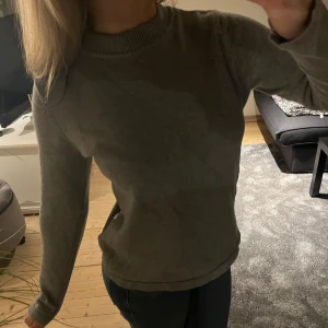 Grå tröja med knappar - Säljer en enkel grå tröja med långa ärmar, guld knappar på sidan och hög hals. Knapparna går såkalrt att knäppa upp och innanför sitter ett rosa band!🎀 Har en liten fläck på baksidan men annars i bra skicka i storlek 146-152 men passar som xs och s!