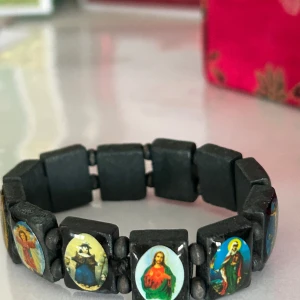 Svart armband med religiösa motiv - Unikt svart armband med flera rektangulära pärlor, var och en prydd med olika religiösa motiv. Elastiskt band för enkel passform. Perfekt för den som vill bära med sig symbolik och stil.