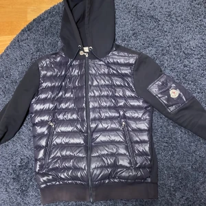 En väldigt fin cardigan ifrån Moncler - Snygg Maglia Con Cappuccio cardigan från Moncler med huva och dragkedja. Detta är en väldigt sällsynt modell 