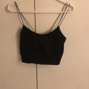 Svart topp från Bik Bok - Snygg svart topp från Bik Bok med tunna axelband. Perfekt för en stilren look. Tillverkad i en mjuk och stretchig polyesterblandning. Toppen är perfekt både till träning men även till vardags. Den är i storlek S-M men skulle säga att den passar S-L🥰🥰