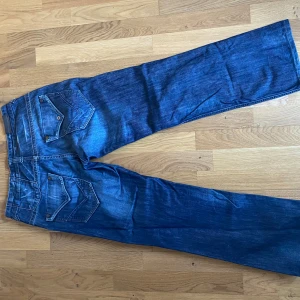 Blå jeans från Diesel - Snygga blå jeans från Diesel med klassisk femficksdesign och knappgylf. Jeansen har en avslappnad passform och är perfekta för en casual look. Detaljerad sömnad på bakfickorna ger en extra touch.