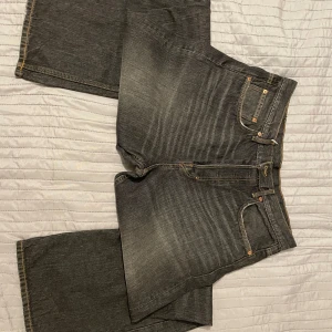 Grå/svarta jeans från Weekday - Säljer ett par grå/svarta jeans från Weekday i modellen Time Loose Bootcut. De har en loose passform och klassisk femficksdesign med knapp och dragkedja. Perfekta för en avslappnad stil. Köpt:699kr
