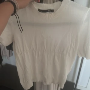 Vit kortärmad tröja från 157 - Säljer en stilren vit tröja från 157 i storlek S. Tröjan har korta ärmar och en rund halsringning med ribbade kanter. Perfekt för en enkel och avslappnad look.