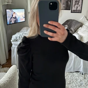 Svart långärmad tröja med puffärmar - Snygg svart tröja med långa ärmar och puffdetaljer vid axlarna. 