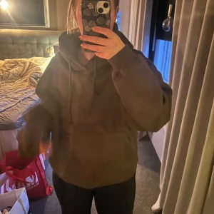Brun hoodie med tryck - Säljer en brun hoodie med tryck på ryggen. Den har en stor och bekväm passform med långa ärmar och en klassisk huva. Perfekt för en avslappnad stil.