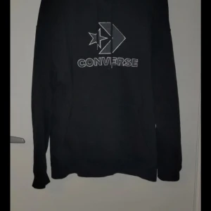 Svart hoodie från Converse - Säljer en svart hoodie från Converse med deras ikoniska logga på framsidan. Tröjan har långa ärmar och en klassisk huva. Perfekt för en avslappnad stil.