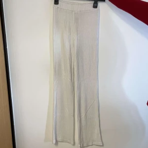 Vita ribbade byxor från Gina Tricot - Snygga vita ribbade byxor från Gina Tricot i en mjuk och bekväm design. Byxorna har en hög midja och en rak passform som ger en stilren look. Perfekta för en avslappnad stil.