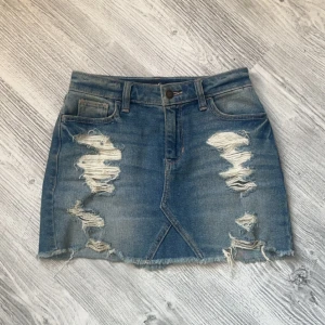 Jeanskjol - Snygg blå jeanskjol från Hollister med slitna detaljer. Längd 33cm Midja 66 cm runt hela.W23