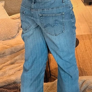 Blå jeans med broderad ficka - Snygga blå jeans med en unik broderad detalj på bakfickan. De har en klassisk femficksdesign och en bekväm passform. Perfekta för en avslappnad stil.