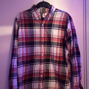 Rutig skjorta från Levi's - Snygg rutig skjorta från Levi's i rött, vitt och svart. Skjortan har långa ärmar och knappar framtill. Perfekt för en avslappnad stil med en klassisk touch. Skriv om ni har frågor!