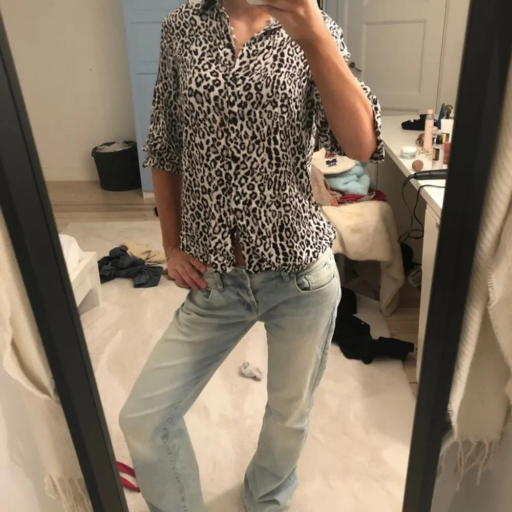 Snygg leopardmönstrad skjorta med knappar framtill. Perfekt för att ge din outfit en trendig touch. Skjortan har en avslappnad passform och trekvartsärmar.. Paidat.