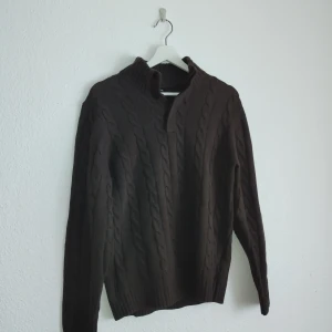 Brun kabelstickad tröja från Massimo Dutti - Säljer en elegant brun kabelstickad tröja från Massimo Dutti i en lyxig ull- och kashmirblandning. Tröjan har långa ärmar och en stilren design med ribbad krage och knappdetalj vid halsen. Perfekt för kyliga dagar!