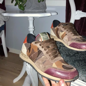 Valentino Rockrunner i camouflage - Snygga Valentino Rockrunner sneakers i en cool mix av brunt och vinrött med camouflage-mönster. Skorna har snörning och en bekväm sula, perfekt för en stilren look.