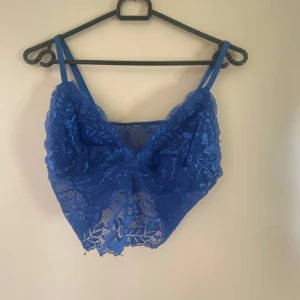 Blå spetslinne från Shein - Snygg blå spetslinne från Shein med justerbara axelband. Den har ett vackert blommigt spetsmönster och är perfekt för att lägga till en touch av elegans till din outfit.