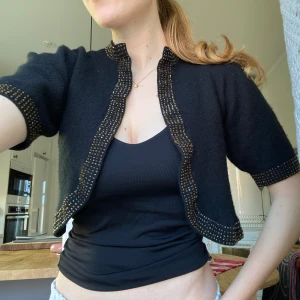 Vintage bolero i svart med pärlor - Vintage bolero topp i 100% ull med såå fina broderade bruna glittriga pärlor på kanterna! Korta puffärmar o croppad modell!