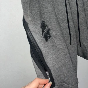 aik nike tech fleecebyxor - Sköna Nike tech fleecebyxor med aik-logga & svarta detaljer. Stor ficka med dragkedja på sidan. Köpta från AIK shop för kanske 4 år sedan så de går inte att få tag i längre. Väldigt sparsamt använda.