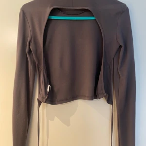 Svart långärmad topp - Säljer en stilren grå långärmad topp. Den är öppen i ryggen och har en knytning längst ner. 