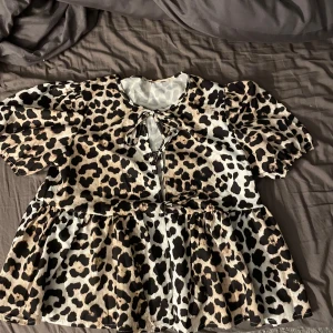 Leopardmönstrad blus med knytning - Säljer en superfin leopardmönstrad blus med korta puffärmar och knytning framtill. Den är i ett mjukt och bekvämt material, perfekt för både vardag och fest! Finns ingen lapp i den då jag köpte den här på plick, men använder den inte, storlek S