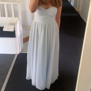 Balklänning bandaeu ljusblå - Hejsan! Säljer nu min balklänning från i somras. Endast använd en gång samt i väldigt bra skick!   I storlek M och går ända ner till tårna på mig som är 164cm. Diskret dragkedja baktill. 