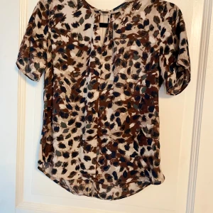 Mönstrad blus från Stockh LM - Säljer en fin blus från Stockh LM med ett coolt mönster i bruna, blå och beige toner. Blusen har korta ärmar och en avslappnad passform. I fint skick!🤎