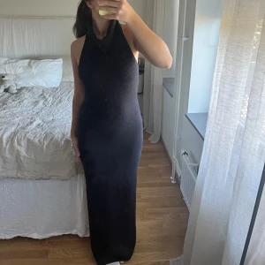 Stickad långklänning  - Säljer min fina svarta stickade långklänning från NA-KD. Använd fåtal gånger och i superfint skick. Den har en halterneck, öppen i rygg och en liten slits. Storlek S. Tjock i matrialet så passar bra till höst/vinter.