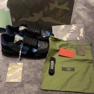 Valentino rockrunners i blått och svart - Snygga Valentino rockrunners med ett coolt camouflage-mönster i blått och svart. Perfekta för att ge din outfit en lyxig touch och en stilren outfit! Splitternya aldrig använda, har av er vid frågor eller funderingar!