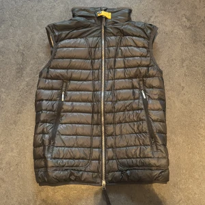 Svart dunväst från Parajumpers - Snygg svart dunväst från Parajumpers med dragkedja och hög krage. Västen har en quiltad design och praktiska fickor med dragkedja. Perfekt för kyligare dagar när du vill hålla stilen.